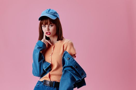 Positive young woman in a cap and denim jacket posing pink background unaltered. High quality photo