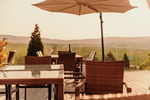 Empty tables in a street cafe overlooking mountains and trees. Sun umbrellas