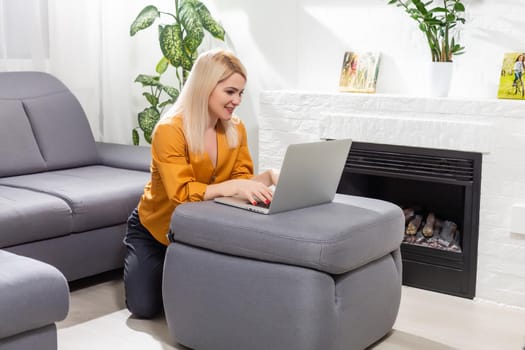 Happy casual beautiful woman working on a laptop sitting in the house.