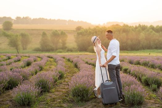 man and woman with suitcase in lavender field.