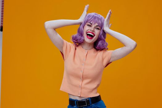 Positive young woman wavy purple hair emotions fun yellow background unaltered. High quality photo