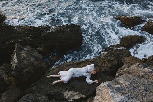 Barefoot woman in white wedding dress on sea shore wet hair view from above. High quality photo