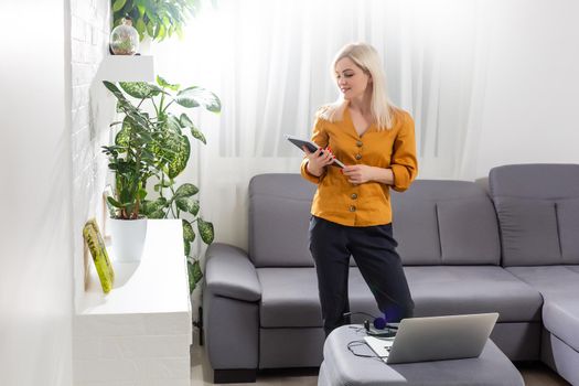 Middle-aged woman reading a message, e-book or information on her tablet computer with a look of excited anticipation at home