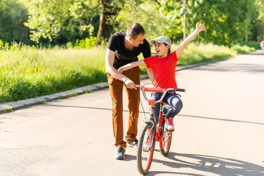 loving father teaching daughter to ride bike.