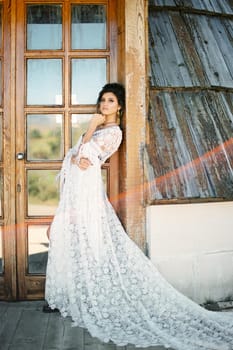 Bride in a white wicker dress leaned against the door frame. High quality photo