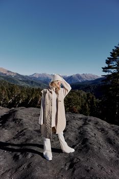 woman in autumn clothes stands on a rock blue sky lifestyle. High quality photo