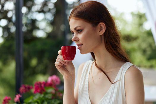 cheerful woman holding a coffee cup standing in the park at summer Happy female relaxing. High quality photo