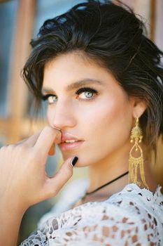 Young girl in a white wicker dress touches her chin with her fingers. Portrait. High quality photo