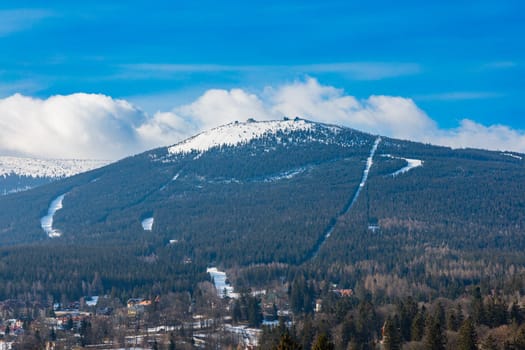 Foggy cloudy landscape seen from long distance of mountain ranges full of snow and giant clouds over it