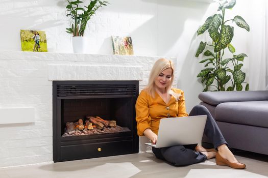 Happy casual beautiful woman working on a laptop sitting in the house.