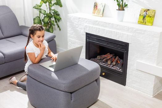Little girl kid studen studying online class with laptop at home, New normal. Covid-19 coronavirus. Social distancing, home schooling.