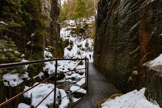 Small footbridge over mountain river between high rocks as path to waterfall