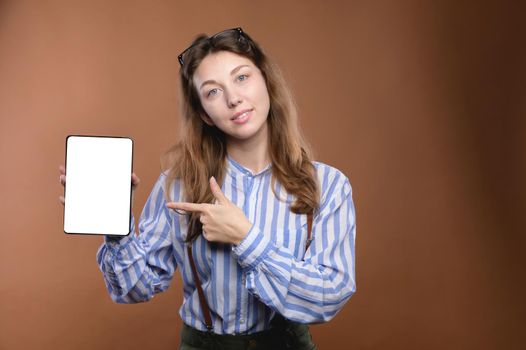 Studio portrait of Caucasian attractive young office woman with electronic tablet. Smiling points to the screen of an electronic tablet. the screen of the device is cut out. Mobile Application Presentation.