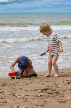 Two little boys are playing on the seashore. Children playing on the beach