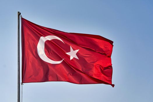 Turkish flag waving in the wind against the background of the sky. White crescent moon and star on red turkish flag