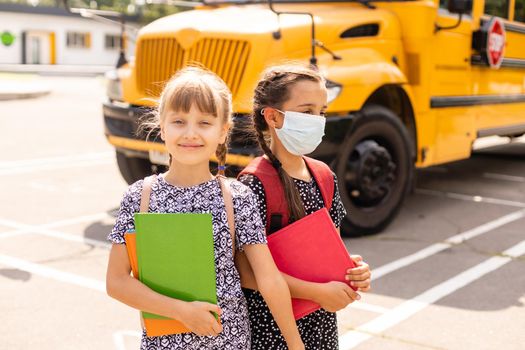 The schoolgirl puts on a mask to prevent colds and viruses. Medical concept. Back to school. Child going school after pandemic over