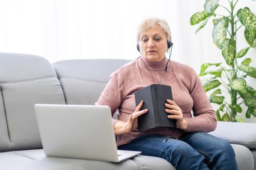 Woman with bible and laptop in front of her connected to online church services durring the covid 19 outbreak