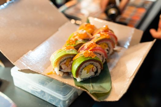 close up of chopsticks taking portion of sushi roll on the table restaurant. eating sushi roll using chopsticks.