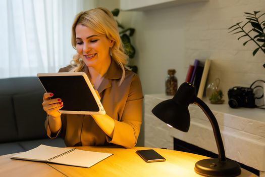 A happy woman girl works remotely from home and communicates via video call with friends and relatives in her office. Distance learning and work online. Using the tablet