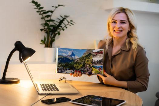 woman holding and presenting photobook near laptop