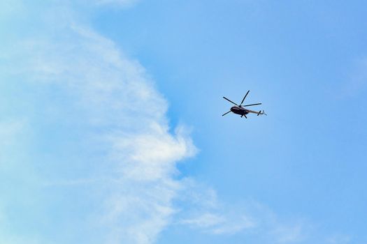 Flying helicopter against the background of a blue sky with spruce clouds. Blank for designers