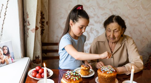 very old grandmother and granddaughter color eggs, preparing Easter cake for Easter at home