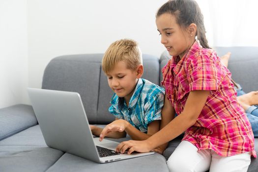 Kids playing with laptop computer at home.