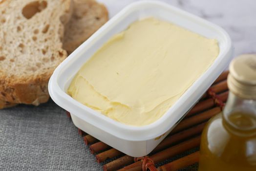 fresh butter in a container with bread on white background .