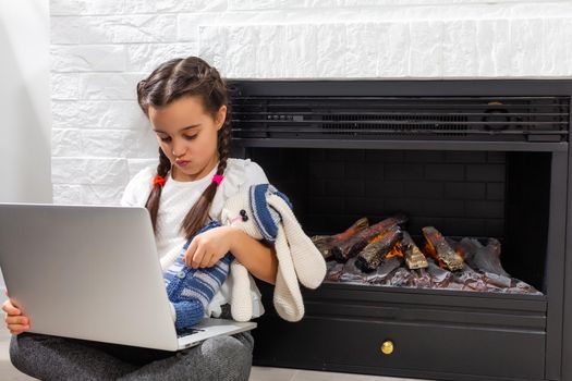 Little girl kid studen studying online class with laptop at home, New normal. Covid-19 coronavirus. Social distancing, home schooling.