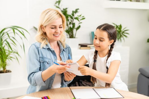 Happy loving family. Mother and her daughter child girl playing and doing homework