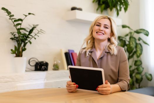 Portrait of a cheerful businesswoman sitting at the table in office and looking at camera