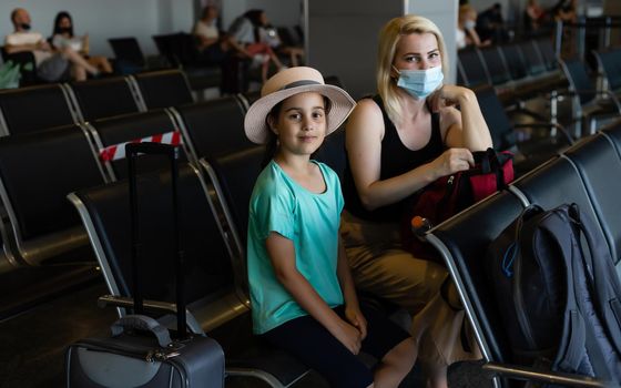 Mother and daughter with face mask going on holiday, at the airport.