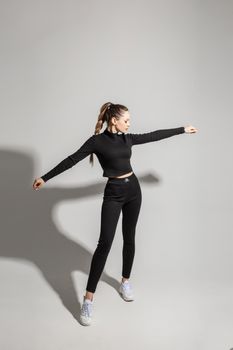 Stylish young girl wearing black sportswear on gray studio background with copy space. Ad mock up for clothes store. High quality photo