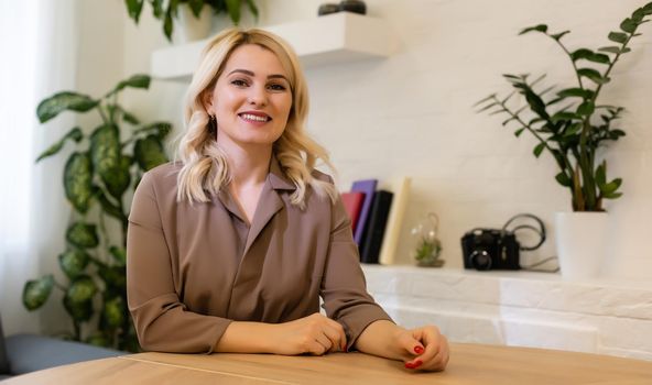 Portrait of a happy casual businesswoman sitting at her workplace in office