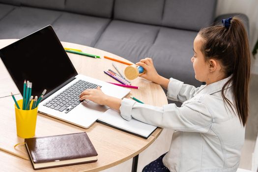 Little girl attending to online e-learning platform class from home while school has been closed during coronavirus outbreak.