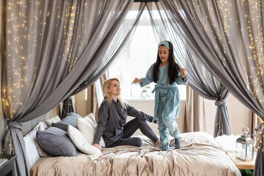 happy mother and daughter playing in bed.