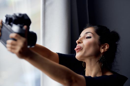 pretty woman holding a camera near the window decoration fashion lifestyle studio. High quality photo