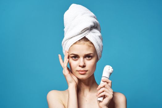 cheerful woman with a towel on the head of the massager in her hands skin care. High quality photo
