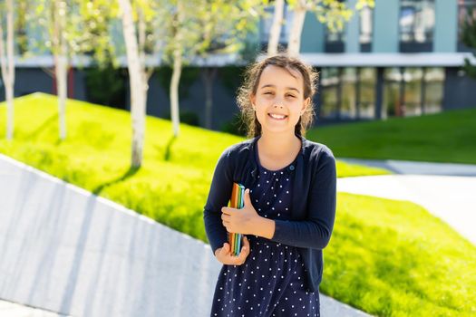 Little beautiful smiling girl holding book, going to school. close up portrait, childhood. kid hugging a book. lifestyle, interest, hobby, free time, spare time.