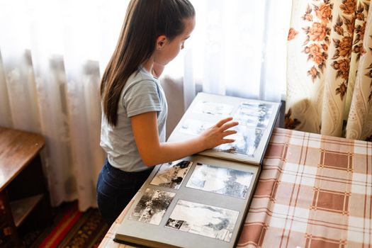 Adorable girl browsing an family album. Vintage style.