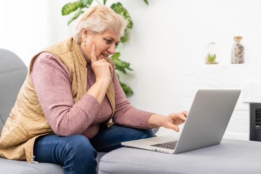 Elderly woman having a video call with her family, smiling and waving. Quarantine time.