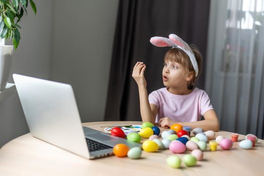 Little girl with her bunny using computer together preparing for easter.