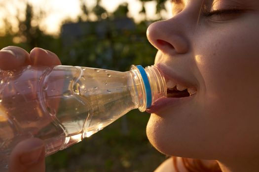 woman drinking water from a bottle face closeup summer. High quality photo