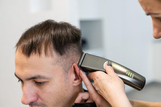 Man getting a haircut by a hairdresser. clipper