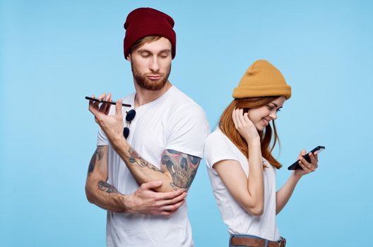 young couple in hats with phones in hands fashion communication. High quality photo