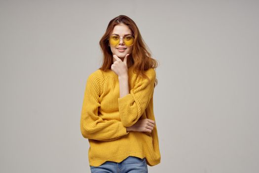 red-haired woman in a yellow sweater fashion glasses studio model. High quality photo