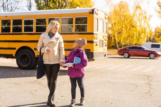 Mother walking her daughter to school bus outside the elementary school