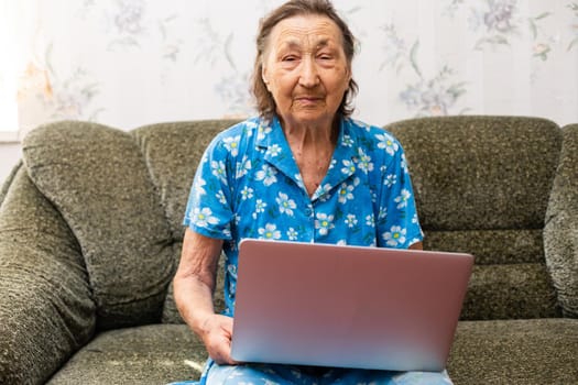 Senior woman looking at screen of laptop computer during video call from home.
