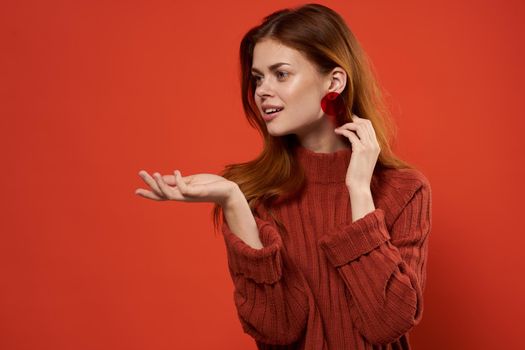 woman in red sweater earrings jewelry red background gesture with hands. High quality photo