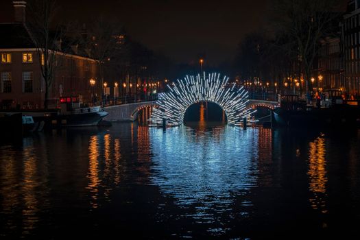 Illuminated bridge in Amsterdam at the Amstel in the Netherlands at night